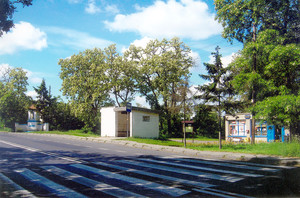 Fot. Celestyn Narożny. Zdjęcie przedstawia fragment szosy na trasie Poznań-Wrocław. Zdjęcie zostało wykonane od strony bramy wjazdowej do Domu Pomocy Społecznej w Jarogniewicach. Widok na sklep, przystanek autobusowy i przydrożną kapliczkę. 