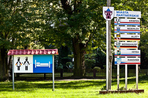 Zajazd u Dudziarza, tuż przed wejściem na teren lokalu - oznaczenie hotelu i restauracji oraz znak z wypisanymi miastami partnerskimi Kościana